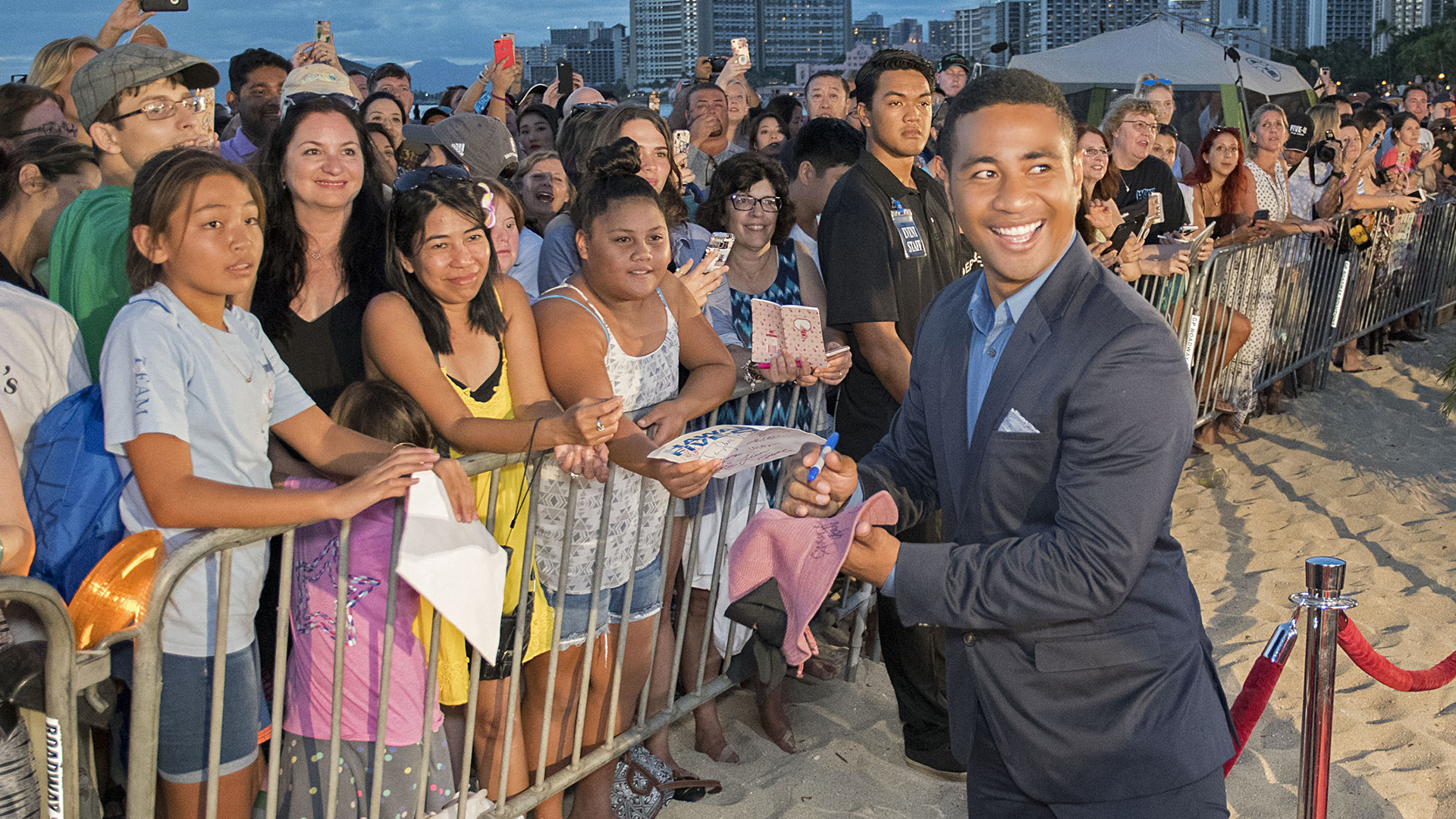 Beulah Koale turns to smile as he signs autographs for fans on the red carpet.