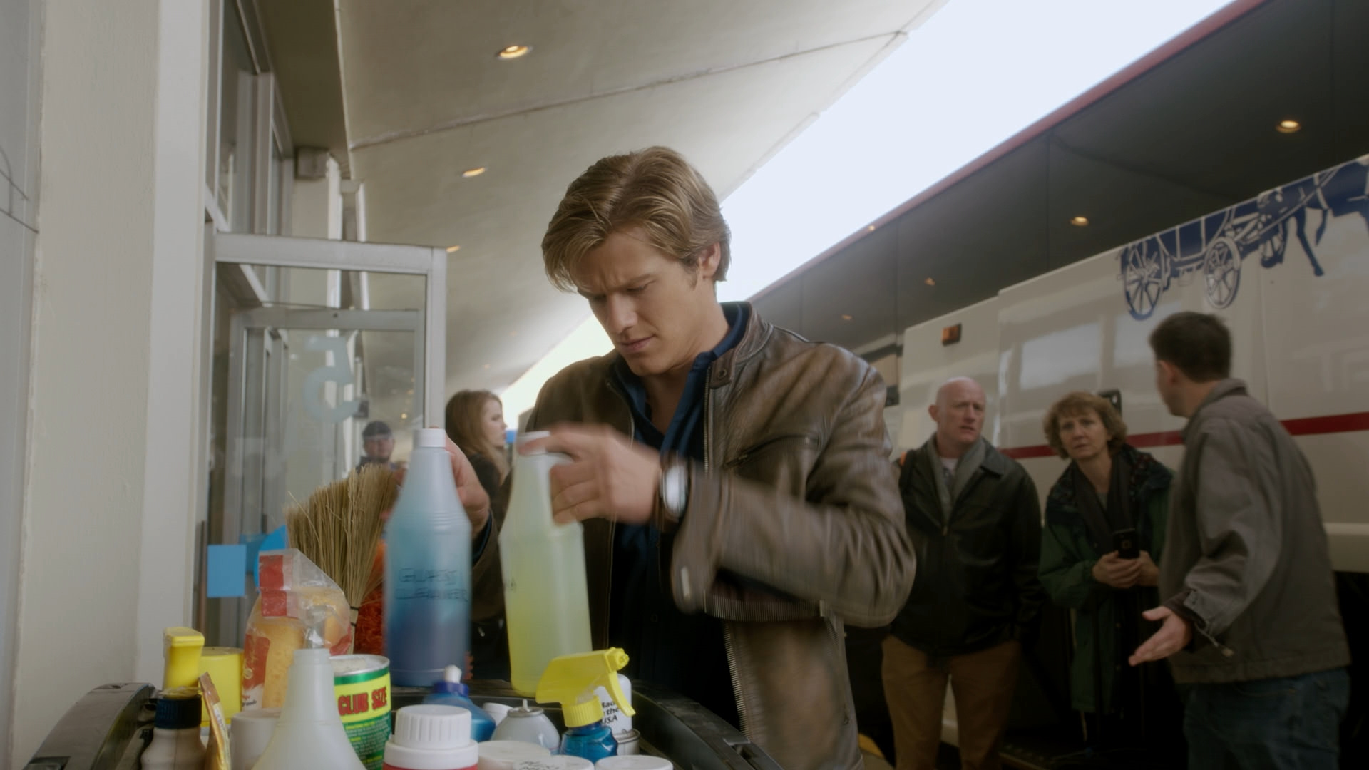 MacGyver rummages through cleaning products.