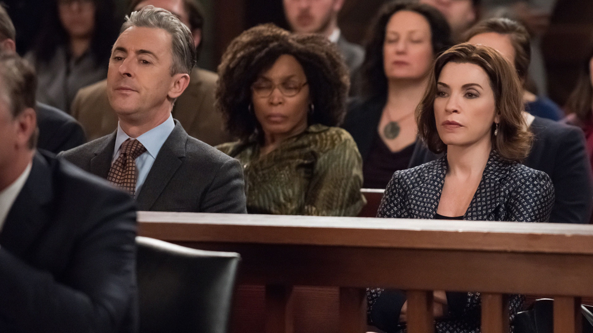 Eli Gold and Alicia Florrick look solemn in the courtroom gallery.